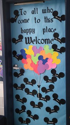 a door decorated with mickey mouse ears and balloons that say welcome to all who come to this happy place