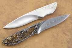 two knives sitting on top of a table next to each other, one with an intricate design