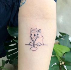 a person with a tattoo on their arm holding a wine glass and looking at it