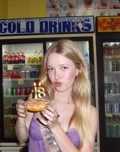 a woman holding a doughnut with candles in her hand