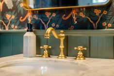 a bathroom sink with gold faucet and soap dispenser next to it