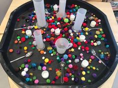 the tray is filled with different colored beads and plastic cups, spoons and forks