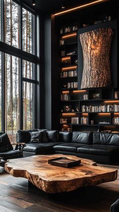 Cozy living room with live-edge coffee table, black walls, leather armchairs, and forest views through tall windows. Moody Built Ins, Dark Mid Century Modern Living Room, Dark Organic Modern, Dark And Cozy Living Room, Moody House Interiors, Cozy Moody Living Room, Dark Earthy Living Room, Black And Brown Living Room, Tree Trunk Art