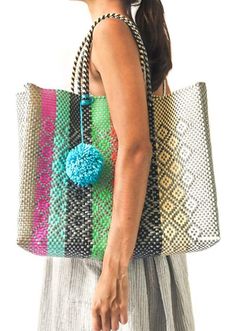 a woman carrying a multicolored bag with a pom - pom