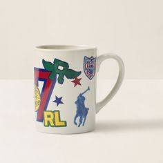 a white coffee mug with various sports logos on the front and side, sitting on a table