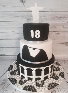 a three tiered cake with black and white frosting on the top, decorated with an image of a man's shirt