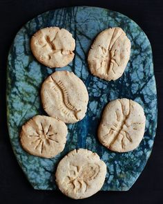 four cookies on a blue plate with green marbled surface and black table top in the background