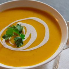 a white bowl filled with soup and garnished with parsley on the side