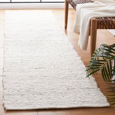 a large white rug in a living room next to a chair and potted plant