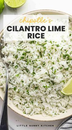 a white bowl filled with rice and topped with cilantro lime wedges on the side