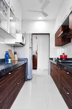 a long narrow kitchen with wooden cabinets and white flooring