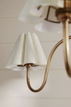 a brass chandelier with white lamps hanging from it