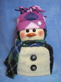 a stuffed snowman wearing a purple hat and scarf with buttons on it's head