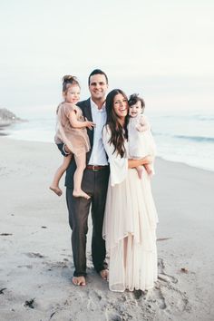 a man and woman holding two children on the beach