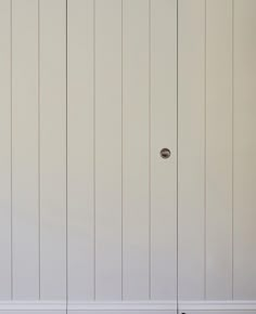 an empty room with white paneling and a door that has a handle on it