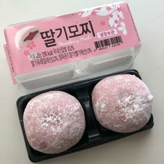 two powdered donuts sitting in a plastic container