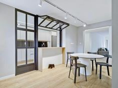 an open concept kitchen and dining area with white walls, wood floors and black framed glass doors