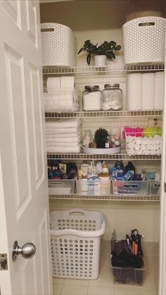 an organized pantry with white baskets and toiletries on the shelves, next to a door