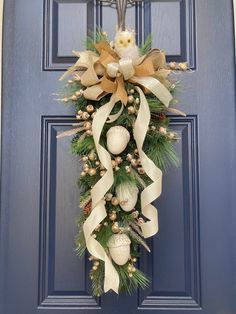 a christmas wreath on the front door with balls and pine cones hanging from it's side