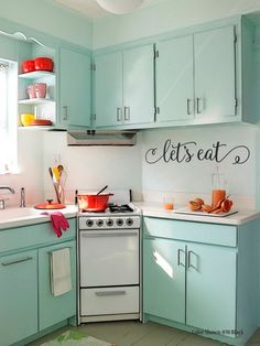 a white stove top oven sitting inside of a kitchen next to a sink and cabinets