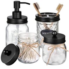 three jars with toothbrushes, soap dispenser and brush in them