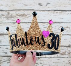 someone is holding up a tiara with the word fabulous 30 written in black and pink