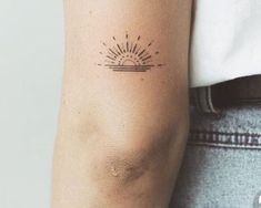 a woman's arm with a small sun tattoo on the left side of her arm