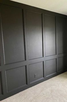 an empty room with black paneling and carpet