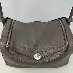 Hermes 2011 Lindy 35 Clemence Bag with Palladium Plated Hardware, Rolled Handles, Single Shoulder Strap (includes Dustbag, relaxed shape, moderate marking at interior and exterior) Designer = Hermes Color = Taupe/Black Material = Leather Condition = Good Height = 8.5 Width = 13.5 Depth = 6.5 Class = Premier Location: Wilmette Item Number: 20201-69 Item ID: 300861 Category: Handle Bag Classic Hobo Bag With Magnetic Closure For Travel, Classic Hobo Bag With Palladium Hardware For Travel, Luxury Hobo Bag With Silver-tone Hardware For Travel, Luxury Taupe Shoulder Bag With Palladium Hardware, Hermes Lindy Bags, Hermes Lindy Mini, Hermes Mini Lindy Bag, Hermes Lindy, Hermes 24/24 Bag