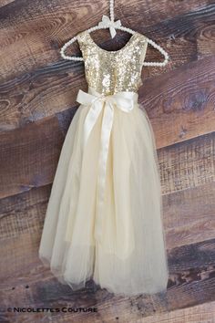 This dress is just beautiful! It is a beautiful shade of ivory/cream tulle on the bottom. The gold sequin top add a fun, elegant feel while the full tulle bottom is a little girl's dream! It also has an embellished ribbon bow sash that is removable. Super comfortable and perfect for your next special event. Nicolette's Couture is a family owned boutique based out of Dubuque, Iowa. When creating looks, comfort is our main priority...regardless of how chic a style is. Our popular special occasion Cream Flower Girl Dress, Sequins Wedding Gown, Sequin Flower Girl Dress, Flower Girl Dresses Champagne, Gold Sequin Top, Sequin Flower, Girls Tulle Dress, Tulle Wedding Gown, Boho Beach Wedding