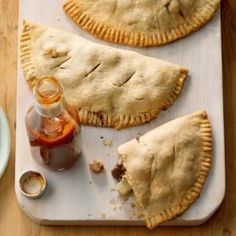 three homemade pastries on a cutting board with sauce