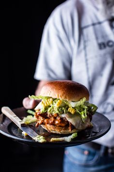 a sandwich with meat and lettuce on a black plate next to a knife