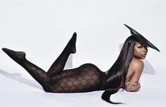 a woman with long black hair laying on the ground wearing fishnet stockings and heels