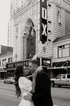 a bride and groom are kissing in front of the fox theatre on their wedding day