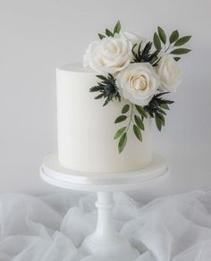 there is a white cake with flowers on the top and bottom, sitting on a stand