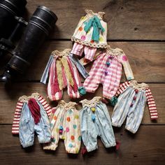 baby clothes hanging on the wall next to a pair of binoculars and an old camera