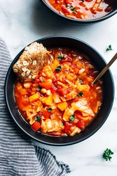 two bowls filled with soup and bread on top of a white countertop next to each other