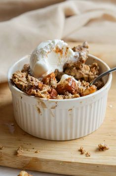 a white bowl filled with food on top of a wooden cutting board next to a spoon