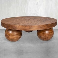 a wooden table with three balls on the top and one ball at the bottom, in front of a white wall