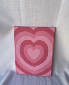 a pink and red heart shaped painting on a white sheet with blue fabric behind it