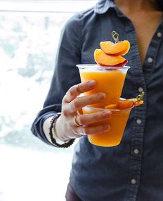 a person holding a drink with orange slices on top