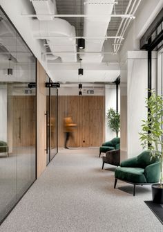 an empty office with green chairs and plants in the center, along with glass walls