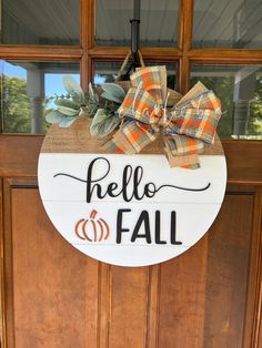 a wooden sign that says hello fall hanging on a front door with a plaid bow