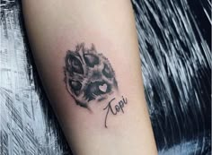 a tattoo on the arm of a woman with an animal paw and name written in cursive ink