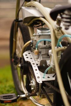 an engine is attached to the front wheel of a motorcycle parked on some grass and dirt