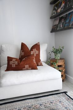 a white couch with two pillows on top of it next to a rug and wooden crates