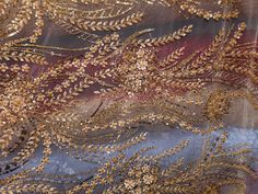 an image of gold and grey fabric with leaves on it's back side, close up