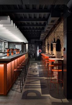 an empty bar with orange stools and black walls