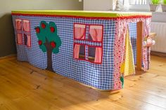 a toy house with windows and trees on the front is sitting on a hard wood floor