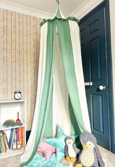 two stuffed animals are sitting in front of a bed with a green canopy over it